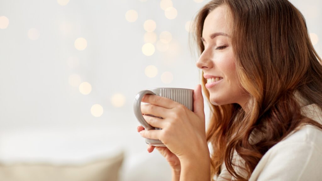 Smiling woman drinking a energizing cup of tea — practicing micro acts of joy for happiness.