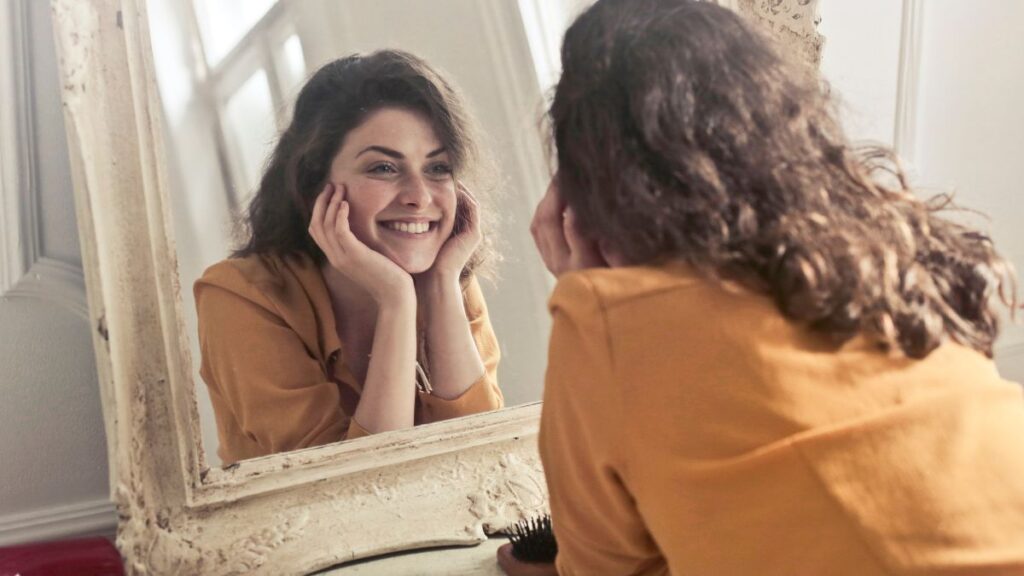 Happy woman smiling at her reflection in a mirror feeling good about herself